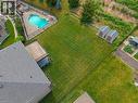 Expansive rear yard featuring a freeform swimming pool with rock features, a paved patio, a wooden deck, and two storage sheds - 38 River Valley Drive, Kitchener, ON 