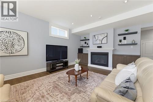 Living area featuring a fireplace with a white mantel, built-in cabinetry, recessed lighting, wood-finish flooring, and a transom window - 38 River Valley Drive, Kitchener, ON 