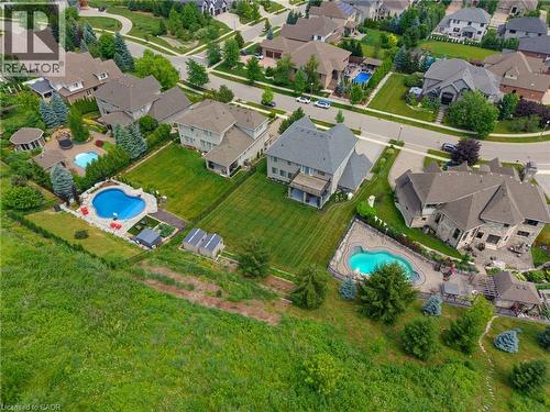 Aerial perspective showcasing multiple properties, each featuring a private swimming pool, manicured lawns, and established landscaping - 38 River Valley Drive, Kitchener, ON 