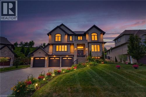 Stately multi-level residence showcasing a stone and stucco facade, a three-car garage, and an inviting main entrance with dual doors - 38 River Valley Drive, Kitchener, ON 