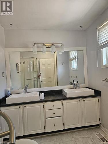 Dual vessel sinks with modern chrome faucets set on a dark countertop - 19 Glenayr Street, Hamilton, ON 