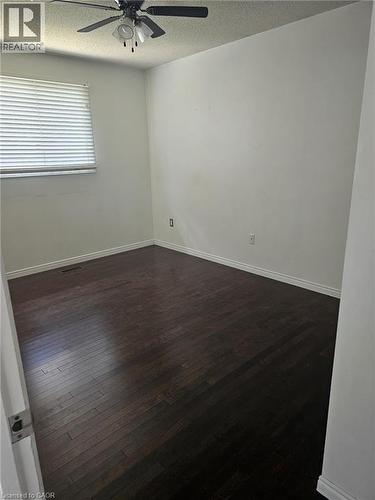 Room featuring dark wood-finish flooring, white walls, and white baseboards - 19 Glenayr Street, Hamilton, ON 