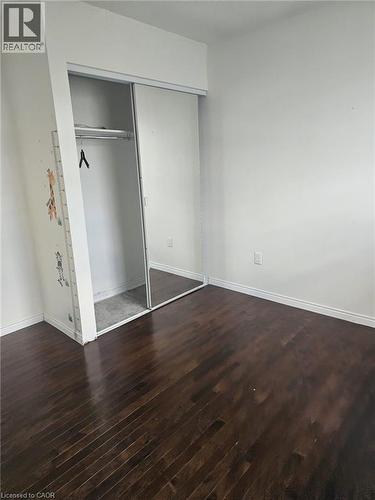 Room featuring dark wood-finish flooring, white baseboards, and a built-in closet with sliding doors, one mirrored - 19 Glenayr Street, Hamilton, ON 