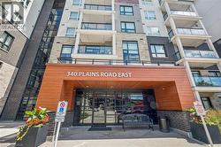 Modern building exterior featuring a wood-finish entrance canopy, dark brick accents, and stone facade - 