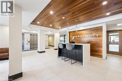 Modern lobby featuring a wood-panel accent wall and ceiling, white tile flooring, and a reception desk with pendant lighting - 