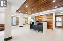 Modern lobby featuring a wood-panel accent wall and ceiling, white tile flooring, and a reception desk with pendant lighting - 340 Plains Road E Unit# 507, Burlington, ON  - Indoor Photo Showing Other Room 