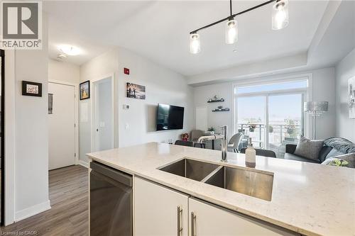 Kitchen island featuring a double basin stainless steel sink, a chrome faucet, and a light-toned countertop - 340 Plains Road E Unit# 507, Burlington, ON - Indoor Photo Showing Kitchen With Double Sink