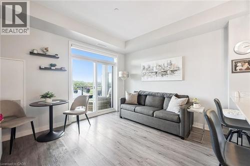 Living area featuring wood-finish flooring and a sliding glass door to an outdoor space - 340 Plains Road E Unit# 507, Burlington, ON - Indoor Photo Showing Living Room