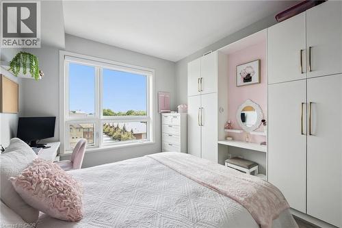 Bedroom featuring a large window, light gray wall color, built-in white cabinetry with gold-tone hardware, and an integrated vanity area - 340 Plains Road E Unit# 507, Burlington, ON - Indoor Photo Showing Bedroom