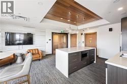 Open-concept living area featuring a central island with integrated microwave, pendant lighting, and wood-panel ceiling accents - 