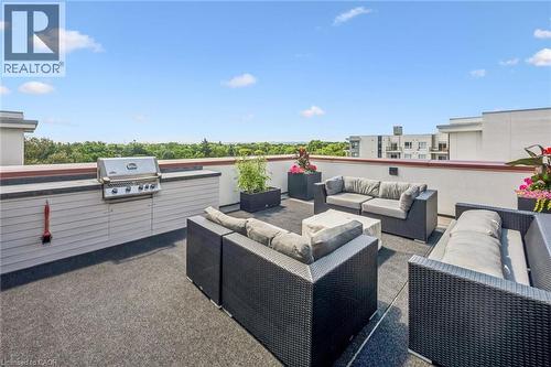 Expansive rooftop terrace featuring a built-in outdoor kitchen with a gas grill, perimeter wall with a contrasting cap, and durable flooring - 340 Plains Road E Unit# 507, Burlington, ON - Outdoor With Deck Patio Veranda