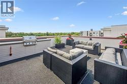 Expansive rooftop terrace featuring a built-in outdoor kitchen with a gas grill, perimeter wall with a contrasting cap, and durable flooring - 