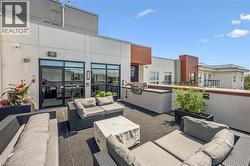 Expansive rooftop patio featuring an integrated built-in grill station, dark-toned flooring, and direct access to interior spaces through large glass doors - 