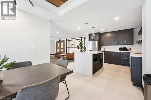 Contemporary kitchen featuring dark wood-finish cabinetry, stainless steel appliances, and an expansive island with a built-in microwave - 340 Plains Road E Unit# 507, Burlington, ON - Indoor