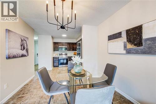 Dining area featuring a modern black chandelier, tile flooring, and direct access to the kitchen - 208 Featherstone Crescent, Kitchener, ON - Indoor Photo Showing Dining Room