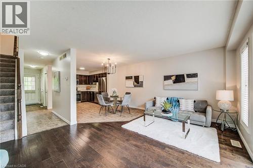 Open-concept living area with dark wood-finish flooring, a contemporary chandelier, recessed lighting, and bright white window blinds - 208 Featherstone Crescent, Kitchener, ON - Indoor Photo Showing Living Room