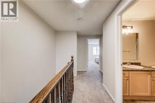 Carpeted hallway featuring a wood-finish bannister and light neutral wall paint - 208 Featherstone Crescent, Kitchener, ON - Indoor Photo Showing Other Room