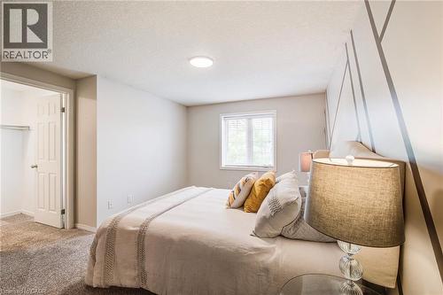 Interior room featuring wall-to-wall carpeting, a window with horizontal blinds, a white ceiling with a flush-mount light fixture, and a wall with a geometric painted design - 208 Featherstone Crescent, Kitchener, ON - Indoor Photo Showing Bedroom