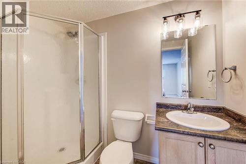Three-piece bath with a corner shower enclosure, a single vanity featuring a laminate countertop, and a wall-mounted mirror with a three-light fixture - 208 Featherstone Crescent, Kitchener, ON - Indoor Photo Showing Bathroom