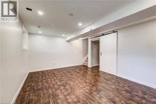Spacious interior room featuring wood-finish flooring, recessed lighting, and a modern barn door - 208 Featherstone Crescent, Kitchener, ON - Indoor Photo Showing Other Room