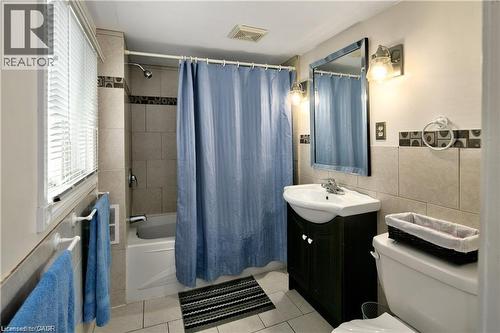 Ceramic tile flooring throughout, featuring a tiled shower surround with decorative accent band and a soaking tub - 42 5Th Lane, Wasaga Beach, ON - Indoor Photo Showing Bathroom