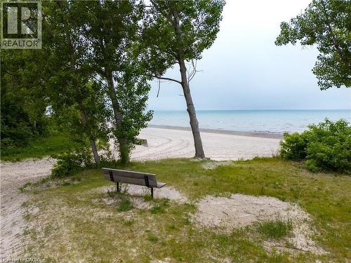 Sandy beachfront area featuring mature trees and a wooden bench - 42 5Th Lane, Wasaga Beach, ON - Outdoor With Body Of Water With View
