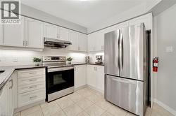 Kitchen featuring white cabinetry, dark countertops, a stainless steel electric range, an overhead stainless steel range hood, and a stainless steel French door refrigerator - 