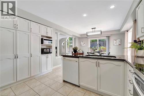 Kitchen featuring white cabinetry, dark countertops, tiled flooring, recessed lighting, and a sliding glass door to the exterior - 35 Dubrick Crescent, Kitchener, ON 