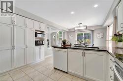 Kitchen featuring white cabinetry, dark countertops, tiled flooring, recessed lighting, and a sliding glass door to the exterior - 