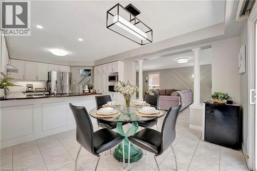 Open-concept kitchen and dining area with white cabinetry, stainless steel appliances, and dark countertops - 35 Dubrick Crescent, Kitchener, ON 