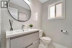 Modern bathroom featuring a white vanity with integrated sink, chrome faucet, and oval mirror - 