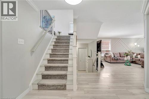 Staircase featuring carpeted treads, white risers, and a contrasting black metal railing - 35 Dubrick Crescent, Kitchener, ON 