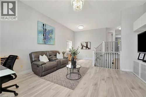 Spacious living area featuring light wood-finish flooring, white walls, and a modern chandelier - 35 Dubrick Crescent, Kitchener, ON 