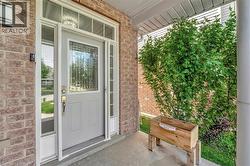 Entryway featuring brick veneer siding, a light gray door with decorative glass, sidelight windows, a transom window, and a concrete porch - 