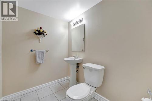 Bathroom featuring neutral wall paint, white tiled flooring, a pedestal sink, and a toilet - 35 Dubrick Crescent, Kitchener, ON 