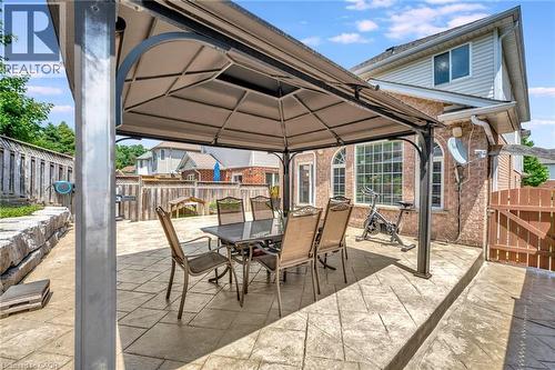 Expansive rear patio featuring a large metal gazebo, patterned concrete surface, and stacked stone retaining wall - 35 Dubrick Crescent, Kitchener, ON 