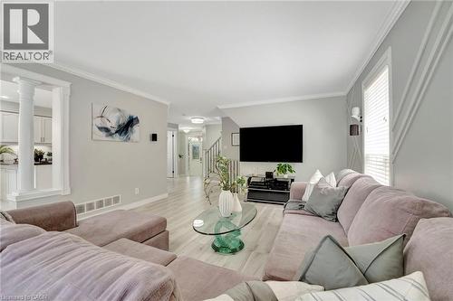 Spacious living area featuring light wood-finish flooring, crown molding, and a decorative accent wall - 35 Dubrick Crescent, Kitchener, ON 