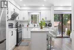 Kitchen with stainless steel appliances, white cabinets, light wood finished floors, and recessed lighting - 