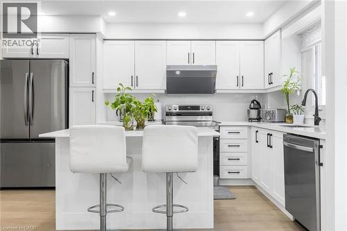 Kitchen with white cabinetry, appliances with stainless steel finishes, a breakfast bar area, a center island, and light wood-style floors - 1118 Avondale Drive, Oakville, ON 