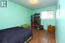 Room featuring wood-finish flooring, a light green wall color, and a window with white trim - 