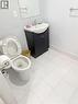 Bathroom featuring a white toilet, black vanity with a white basin sink, and a wall-mounted mirror - 499 Main Street E, Hamilton, ON 