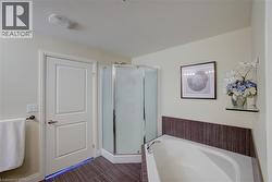 Bathroom featuring a corner shower enclosure with frosted glass, a built-in soaking tub, and tile surround with dark wood-finish accents - 