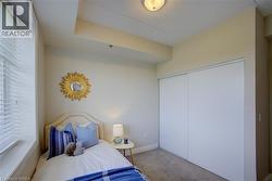 Room featuring a textured upholstered headboard, a window with horizontal blinds, and a built-in closet with sliding doors - 
