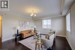 Spacious room featuring dark wood-finish flooring, light-colored walls, crown molding, and large windows - 