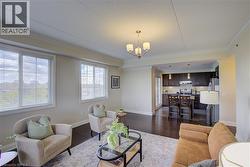 Open-concept living space with dark wood-finish flooring and crown molding - 