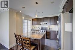 Kitchen featuring dark wood cabinetry, stainless steel appliances, and a central island with a granite countertop - 