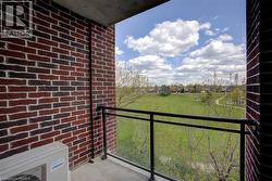 Balcony with glass railing and black frame, featuring a concrete floor and a brick wall - 