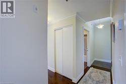 Hallway featuring rich wood-finish flooring, white crown molding, and a built-in closet with sliding doors - 