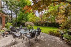 Spacious stone patio overlooking a manicured lawn framed by mature trees and lush plantings - 