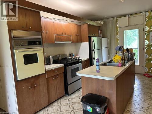 Kitchen featuring wood-finish cabinetry, built-in wall oven, gas range, and a central island with an integrated sink - 11 Wilmont Court, Hamilton, ON 